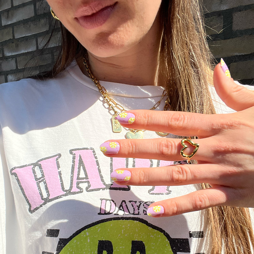 Hand laat nagelstickers met lila en gele citroenen zien