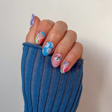 Hand laat blauwe roze nagelstickers zien met vrolijke funky print