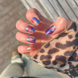 Hand laat nagelstickers met gekleurde swirls en daisy bloemen zien