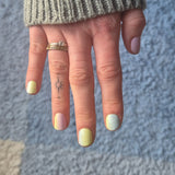 hand laat nagelstickers in pastelkleuren zien boven lichtblauwe ondergrond