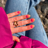 Hand laat nagelstickers met rood-roze verloop zien met roze winterjas en blauwe jeans