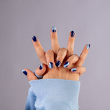2 in elkaar gevouwen handen die nagelstickers tonen met lichtblauwe en donkerblauwe organische vormen