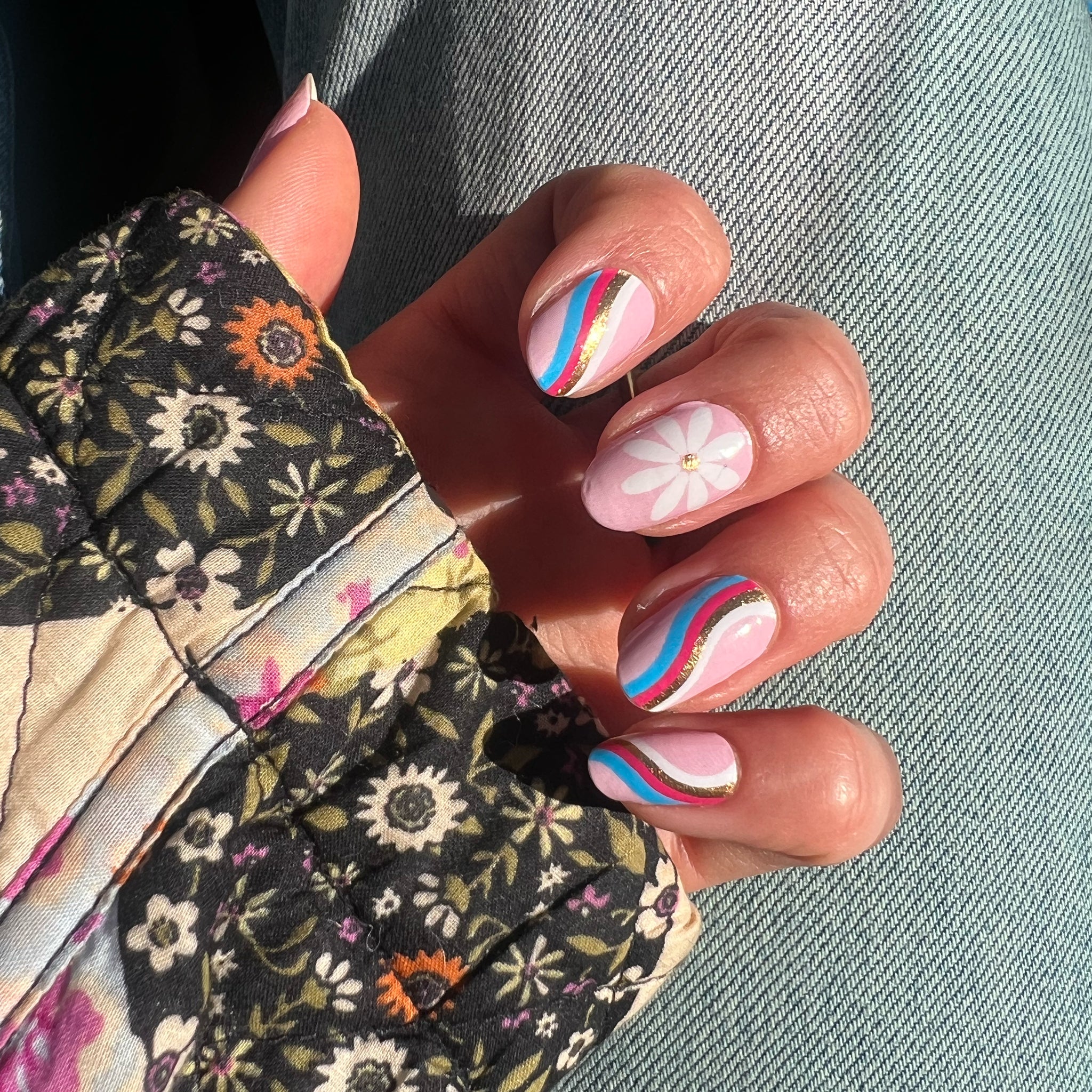 Handen laten lichtroze nagelstickers met bloemen en swirls zien