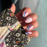 Handen laten lichtroze nagelstickers met bloemen en swirls zien