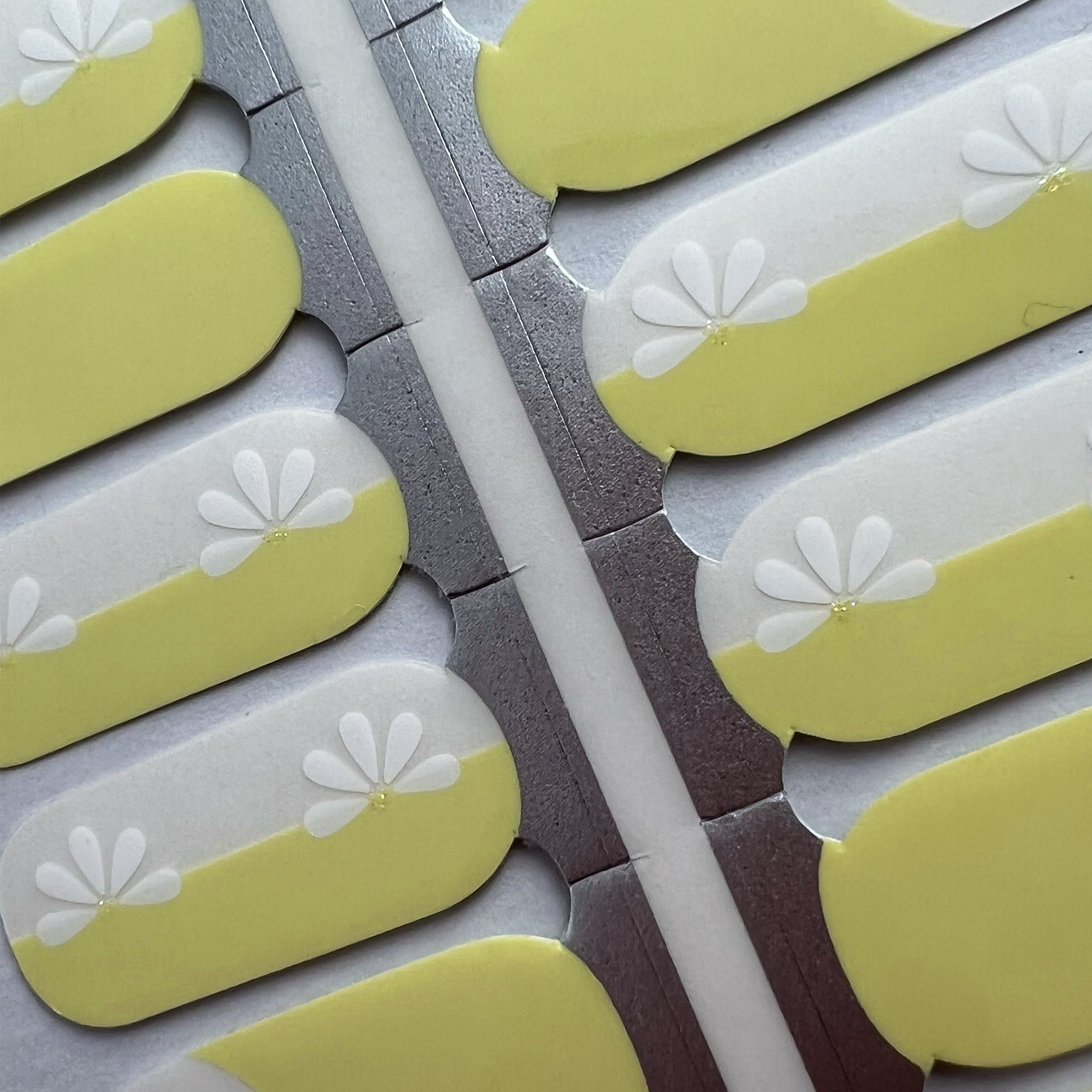 Detail shot van butter yellow nagelstickers met witte bloem