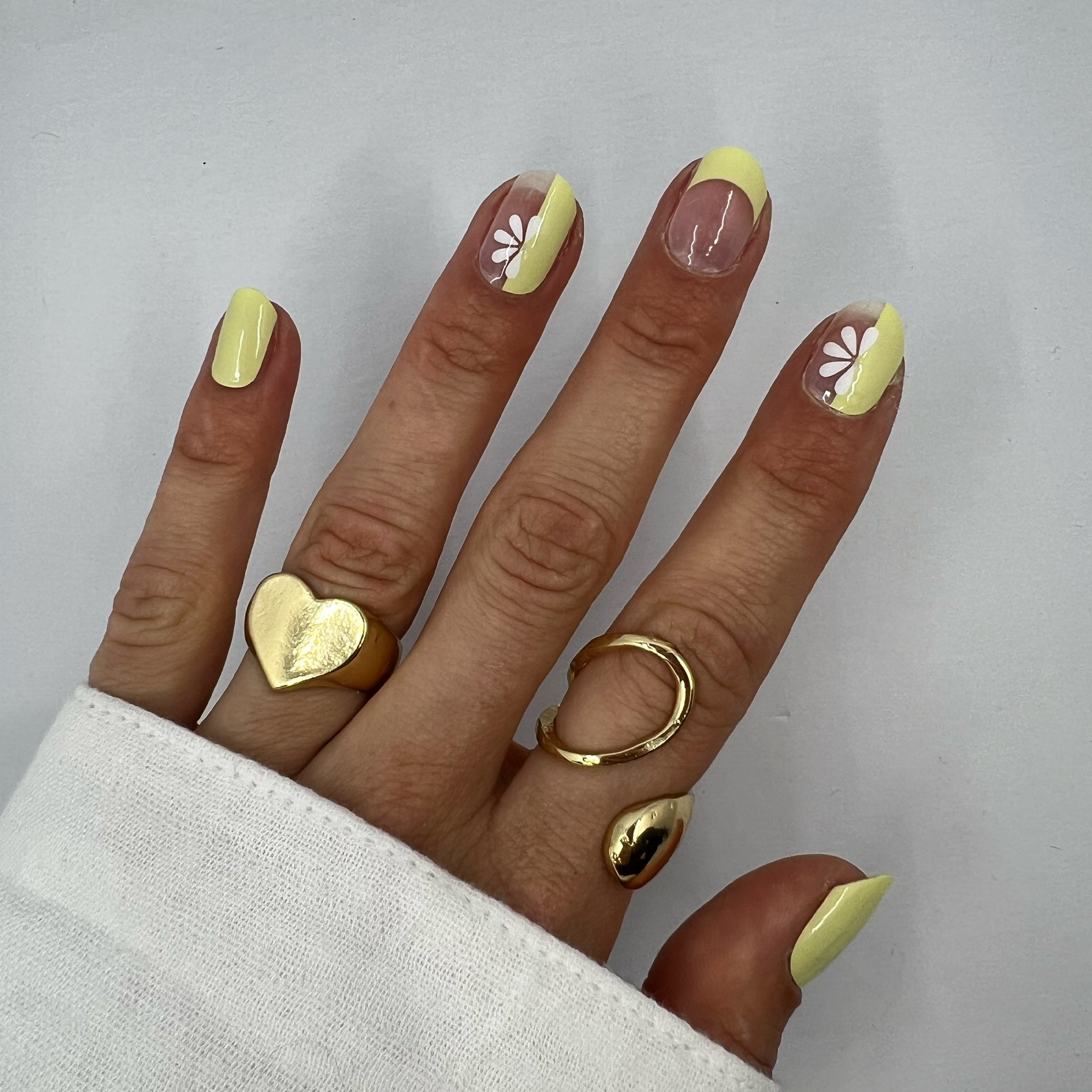 Hand laat butter yellow nagelstickers zien op witte achtergrond met witte blouse