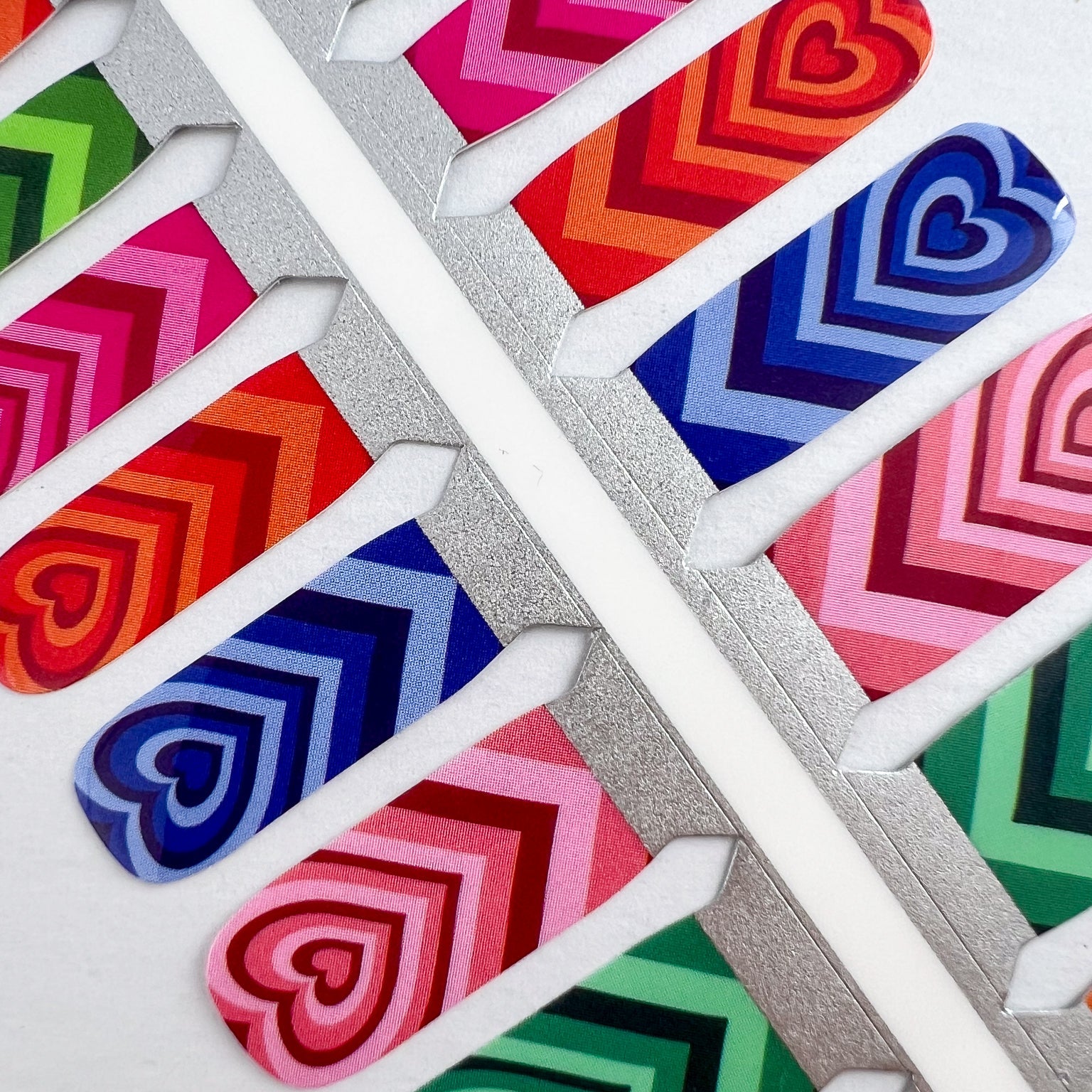 Detailfoto van nagelstickers met hartjes in verschillende kleuren op witte achtergrond