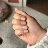 Hand laat nagelstickers in nude kleur met glitters zien met vloerkleed als ondergrond