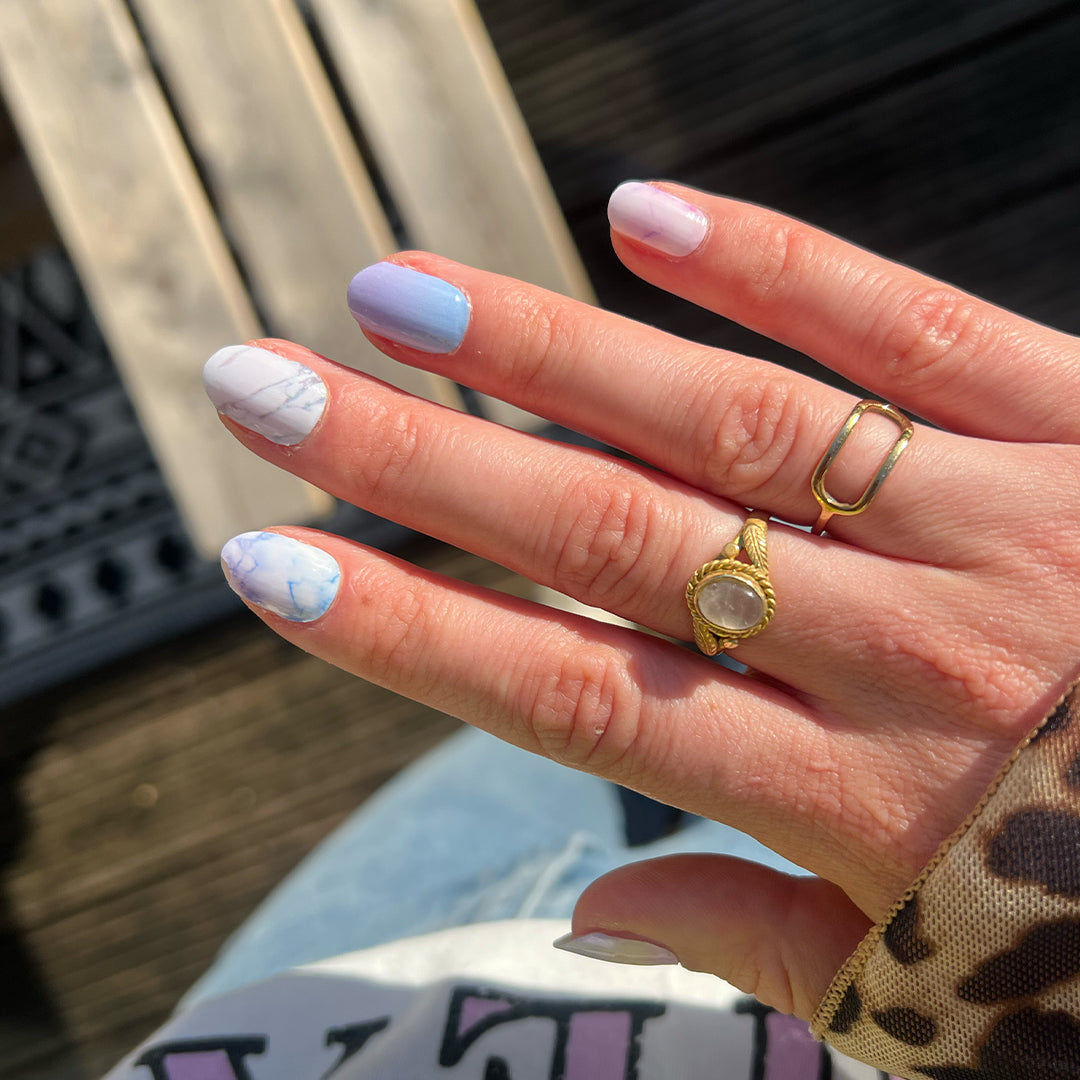 Hand laat nagelstickers met blauwe marmer zien met houten ondergrond