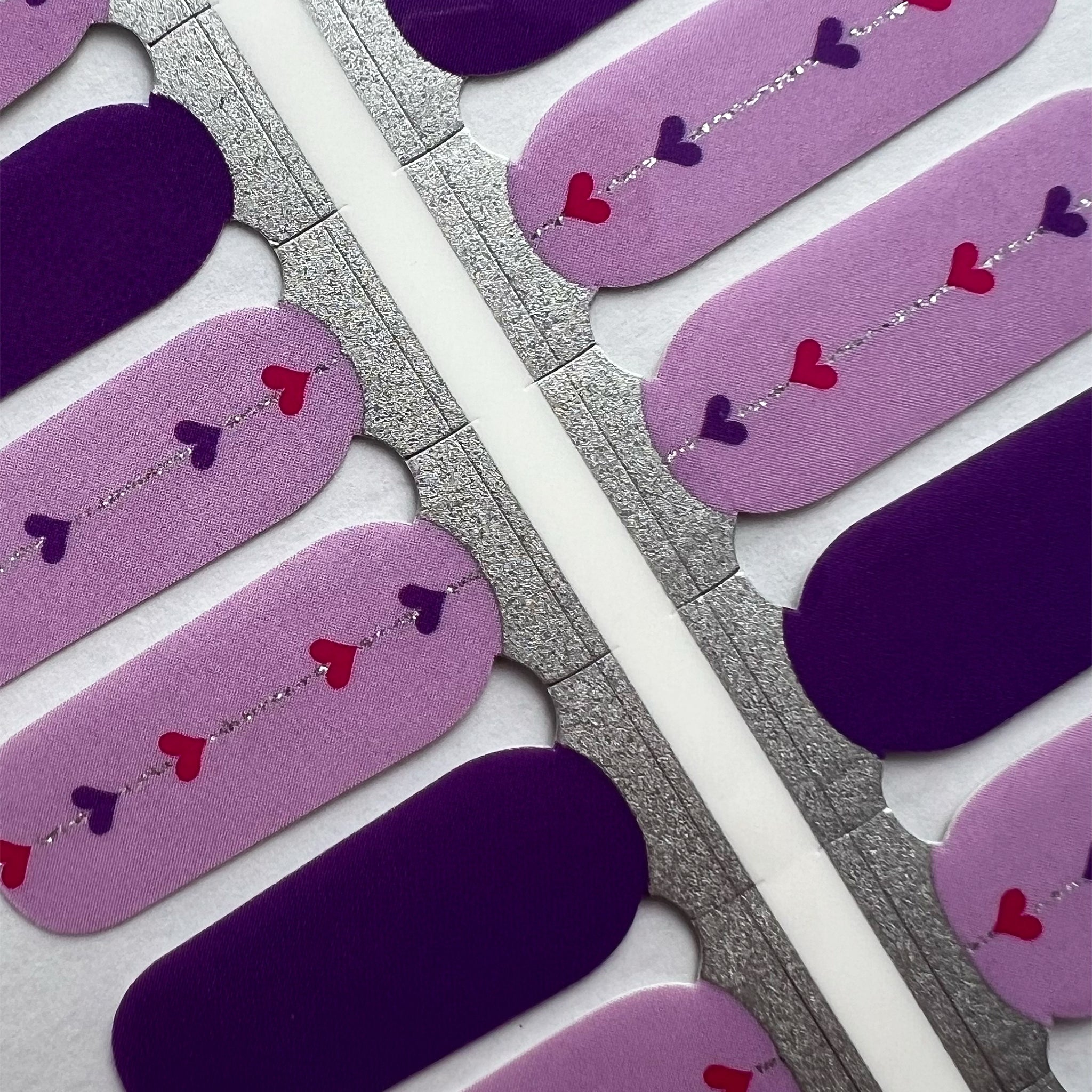 Detailoto van paarse nagelstickers met hartjes op witte achtergrond