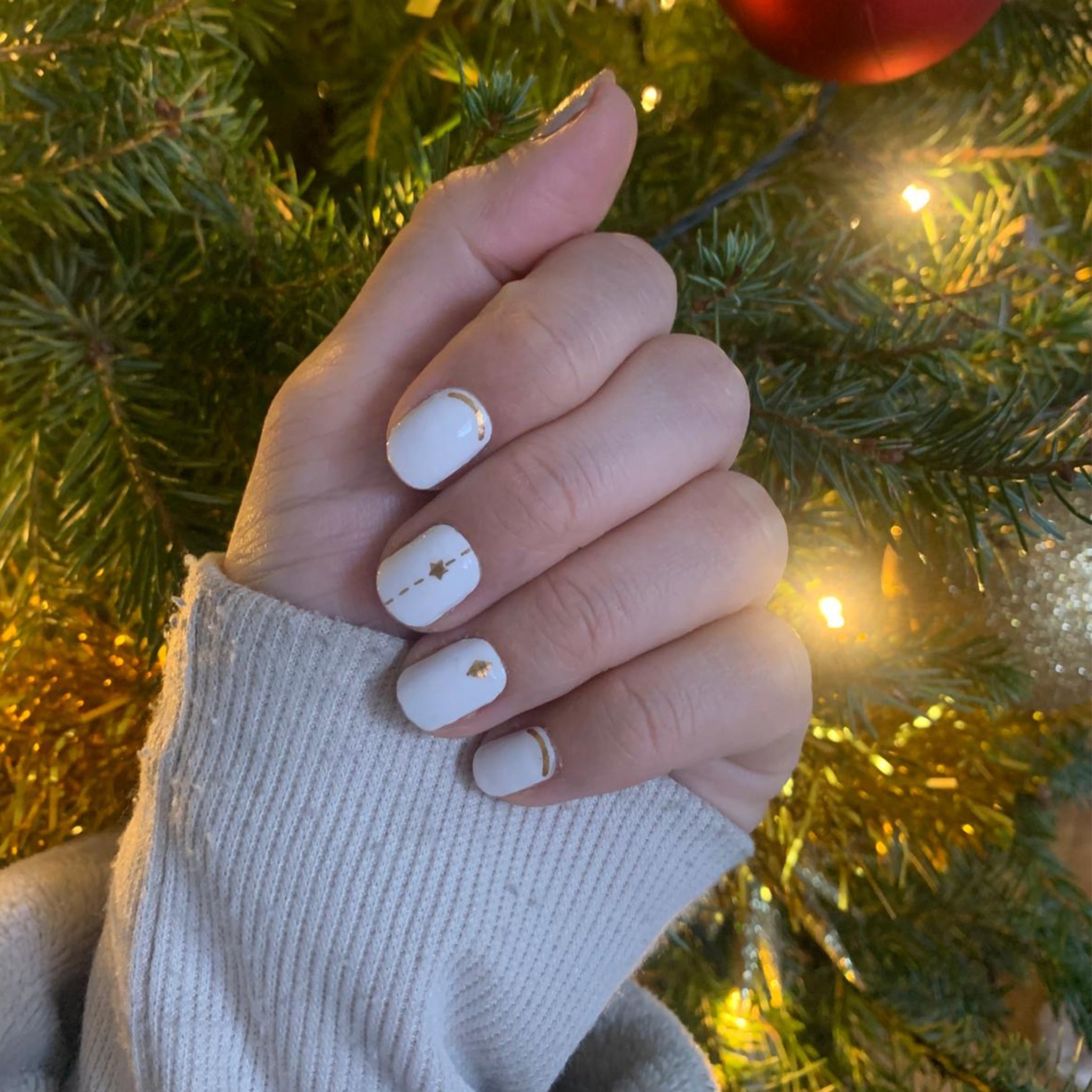 Hand voor kerstboom laat witte met gouden nagelstickers zien
