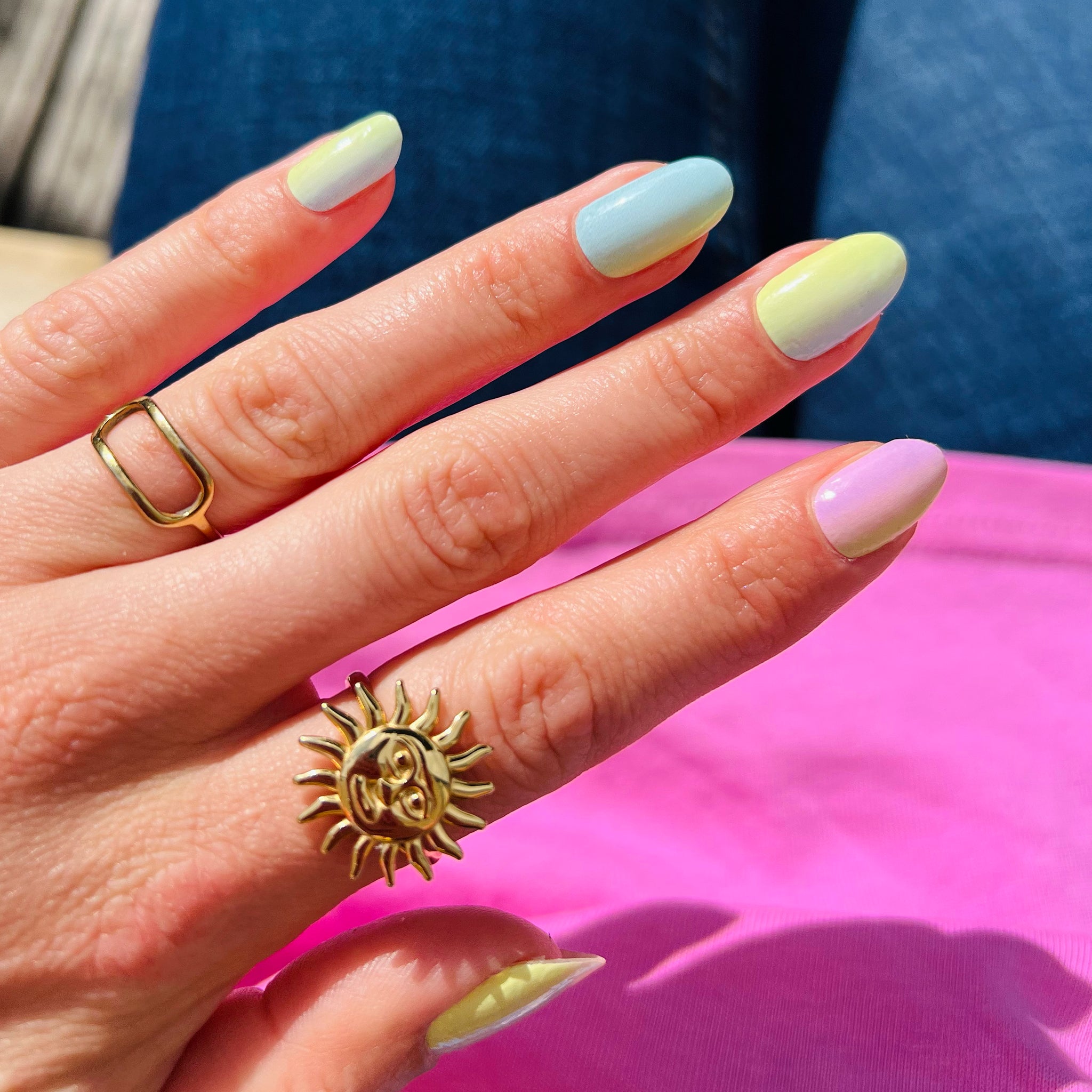 Nagelstickers met pastel roze, geel en blauw boven zittend persoon
