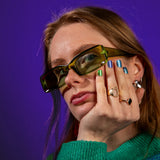 Model met groene zonnebril toont blauw, groene nagelstickers met marmerpatroon op nagels