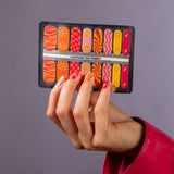 Hand toont nagelstickers met roze, gele en oranje 70's hippie patroon