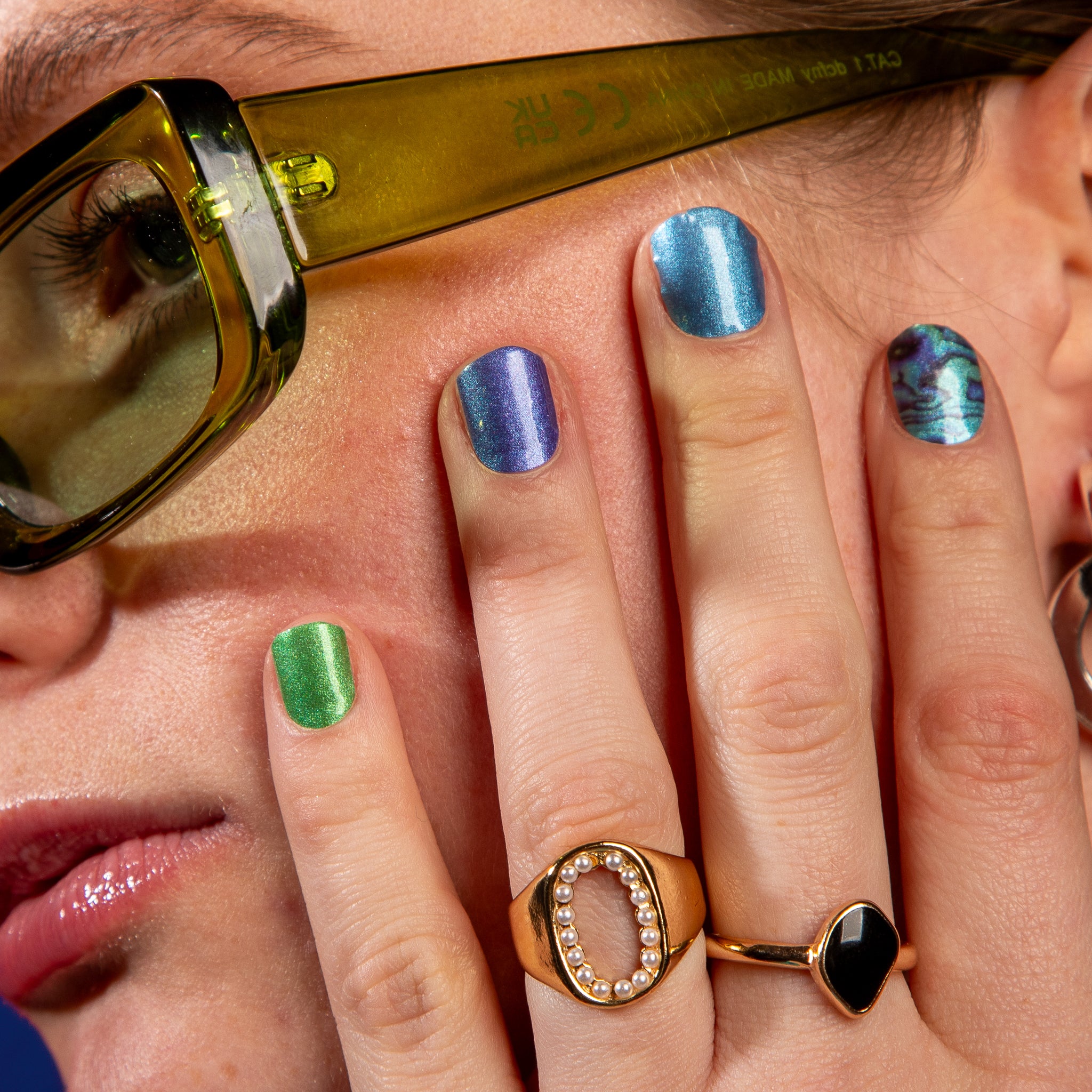 Model toont blauw, groene nagelstickers met marmerpatroon op nagels