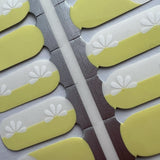 Detail shot van butter yellow nagelstickers met witte bloem