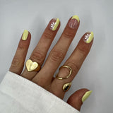 Hand laat butter yellow nagelstickers zien op witte achtergrond met witte blouse