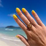 Hand met gele nagelstickers op strand met blauwe lucht en blauw water