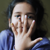 Meisje laat nagelstickers voor kids met lichtroze, smileys en regenbogen zien