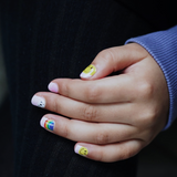 Hand laat nagelstickers voor kids met lichtroze, smileys en regenbogen zien
