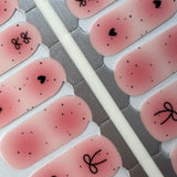 Detail foto van roze nagelstickers met zwarte stipjes en strikjes