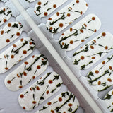 Detailfoto van nagelstickers met witte bloemetjes op witte achtergrond