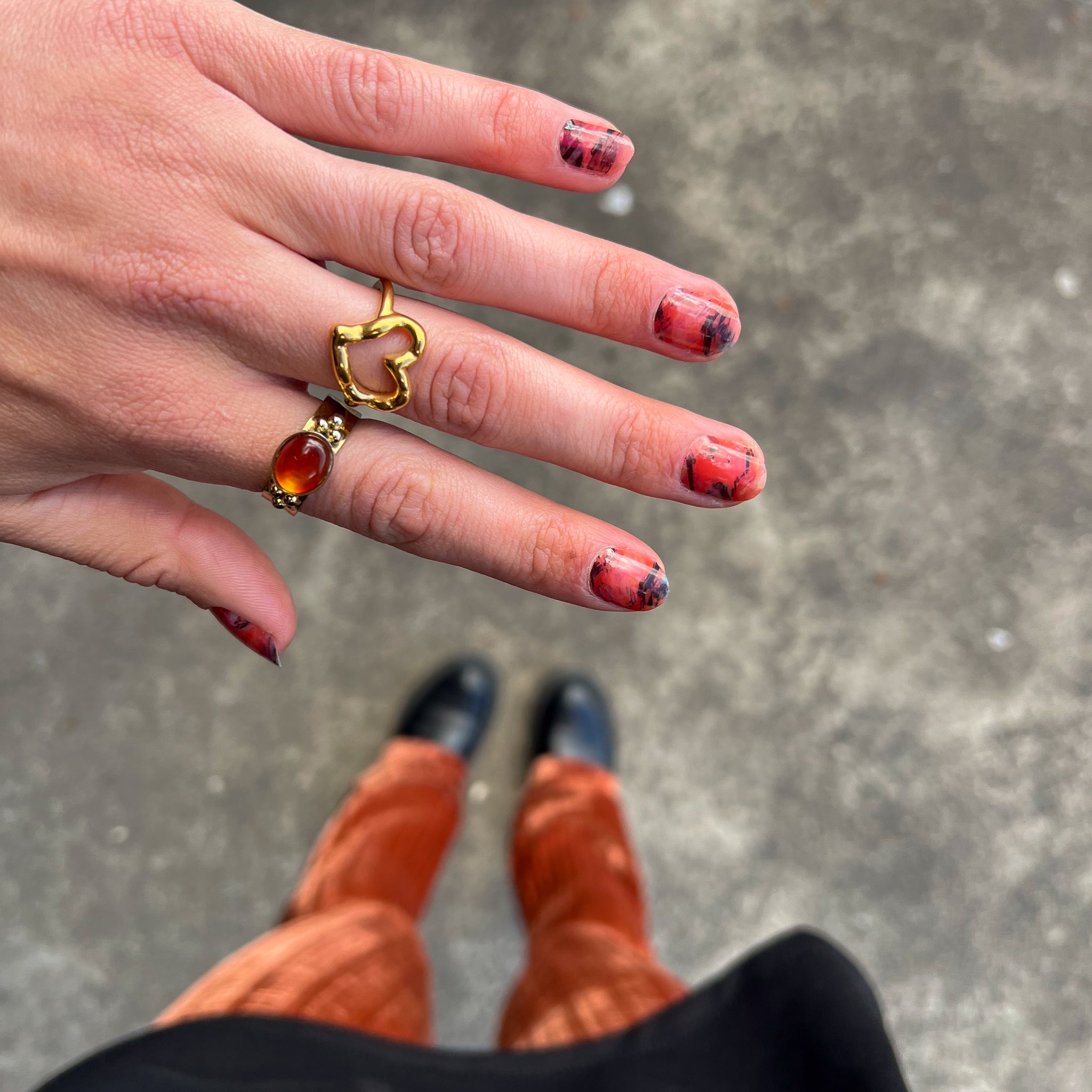 Hand toont nagelstickers met oranje verfpatroon met stenen ondergrond