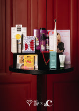 Giftbox met allerlei producten op een tafeltje voor rode achtergrond
