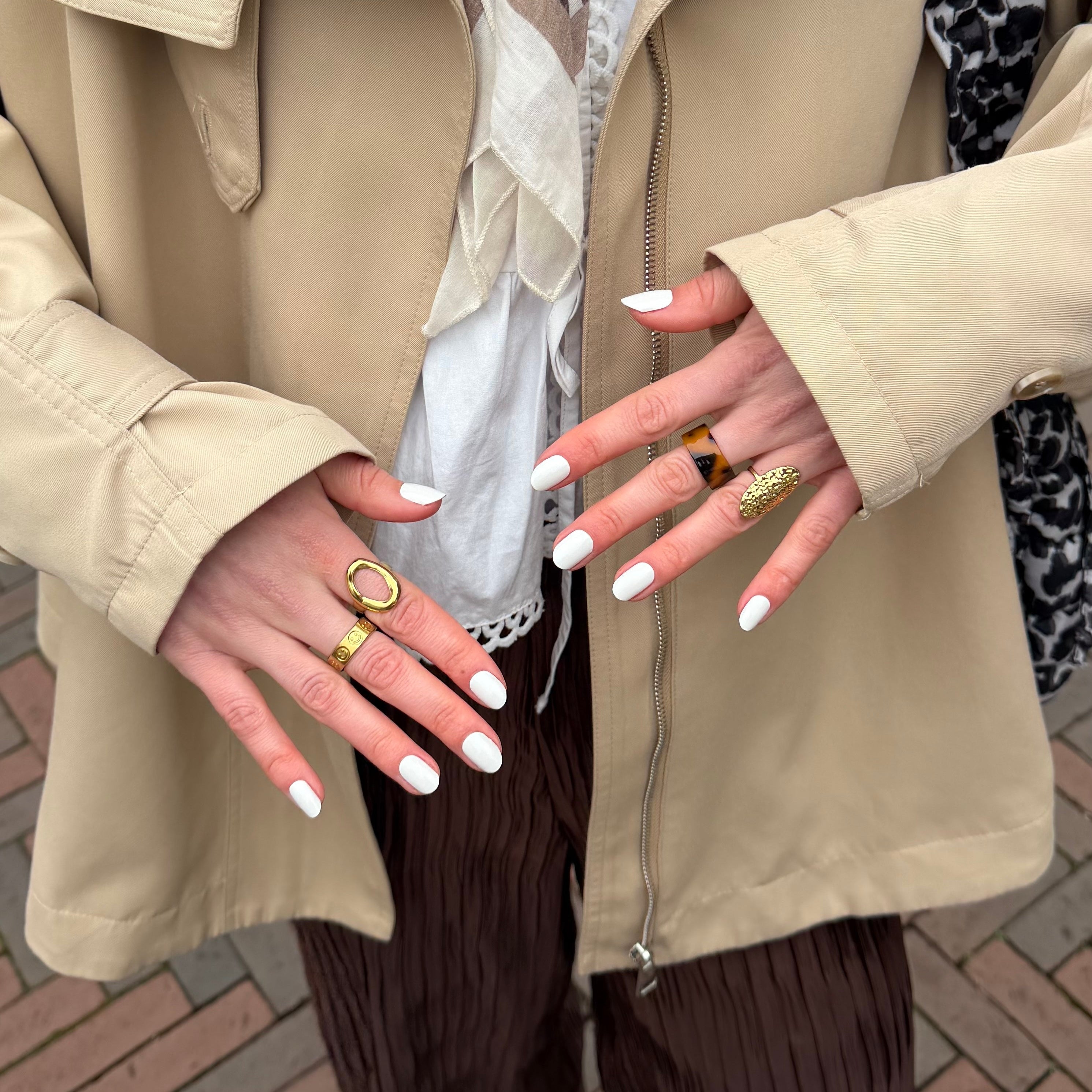 2 handen met gouden ringen laten witte nagelstickers zien