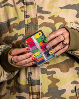 twee handen houden nagelsticker met kleuren en sterren vast met camouflage jasje
