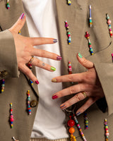 Twee handen laten nagels zien met blazer en kleurrijke kralen