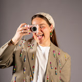 model met kleurrijke kralen blazer maakt foto met fotocamera