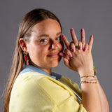 model met haar handen voor gezicht laat nagels zien in gele trui