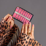 handen laten nagelstickers zien met roze iconen en panterprint jas met franjes